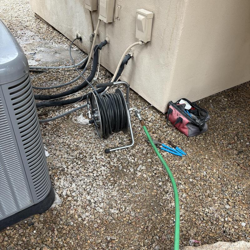 Hydrojetting hose reel and tools on gravel near building