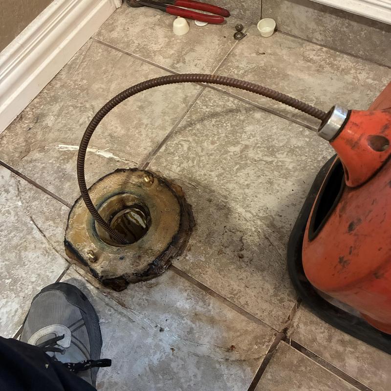 Toilet flange and drain snaking tool on tile floor Toilet flange and drain snaking tool on tile floor