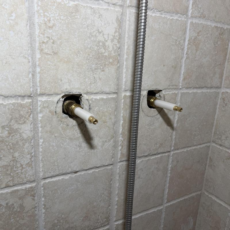 Shower valve stems exposed in tile wall