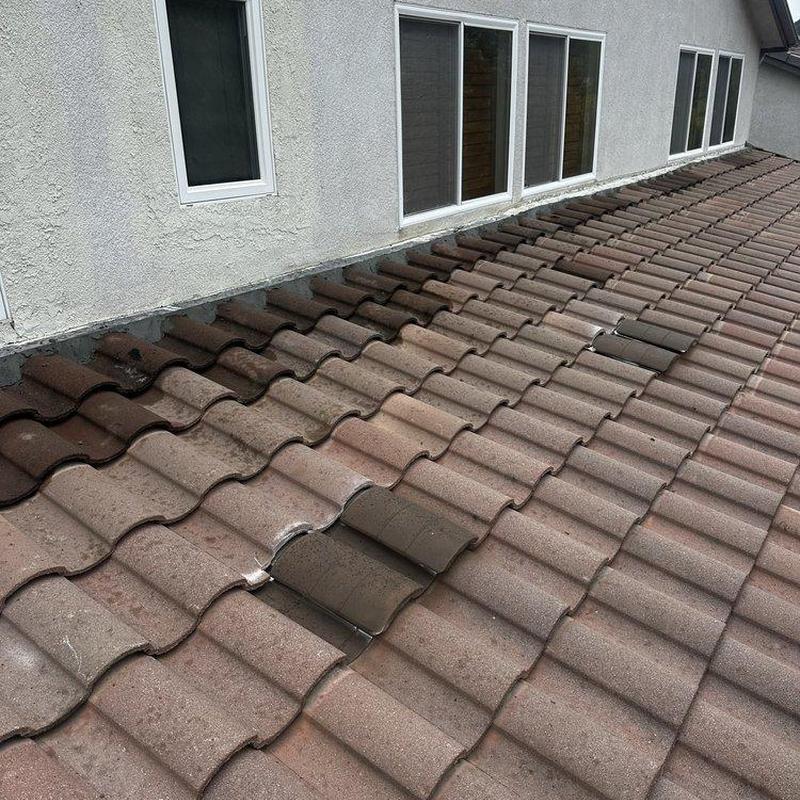 Tile roof with damaged and discolored tiles near windows Tile roof with damaged and discolored tiles near windows
