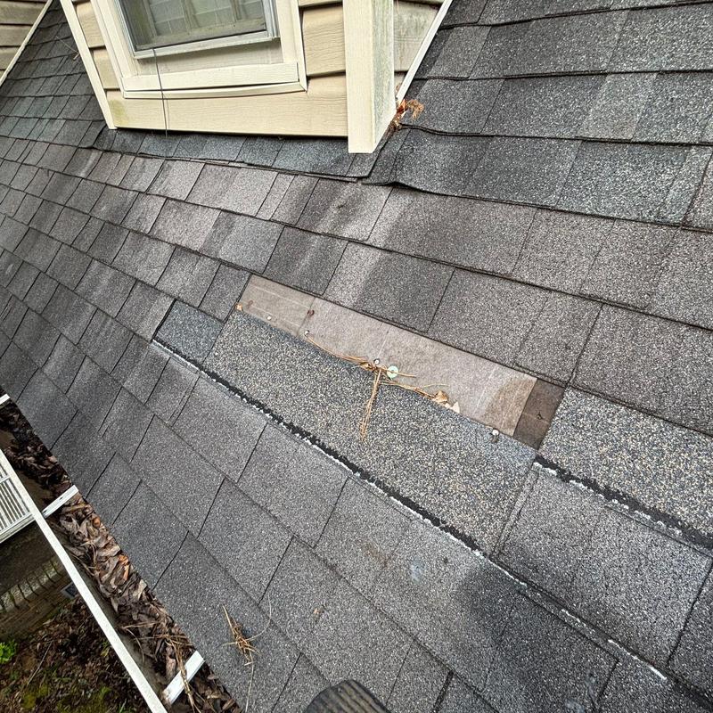 Shingles with exposed fasteners and lifted edges near dormer