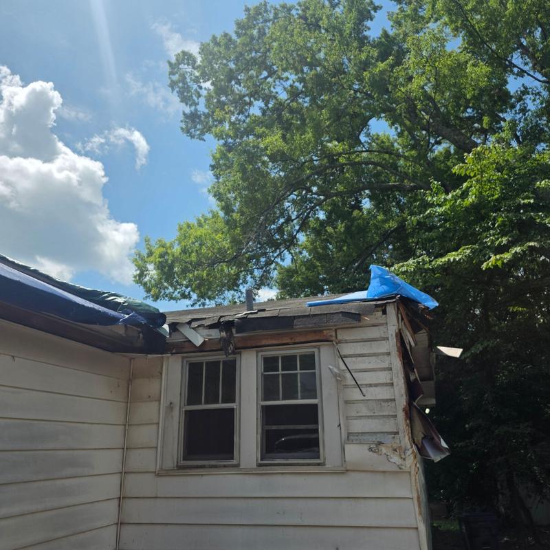 Roof system damage with collapsed sections and tarping