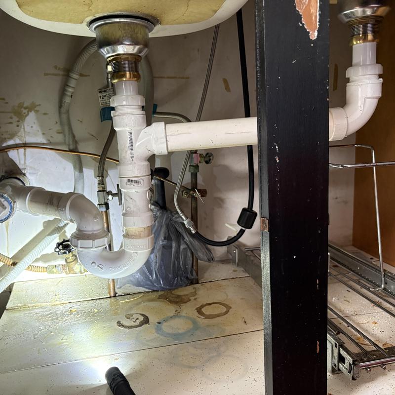 Kitchen sink drainage pipes and brass pop-up assembly under sink