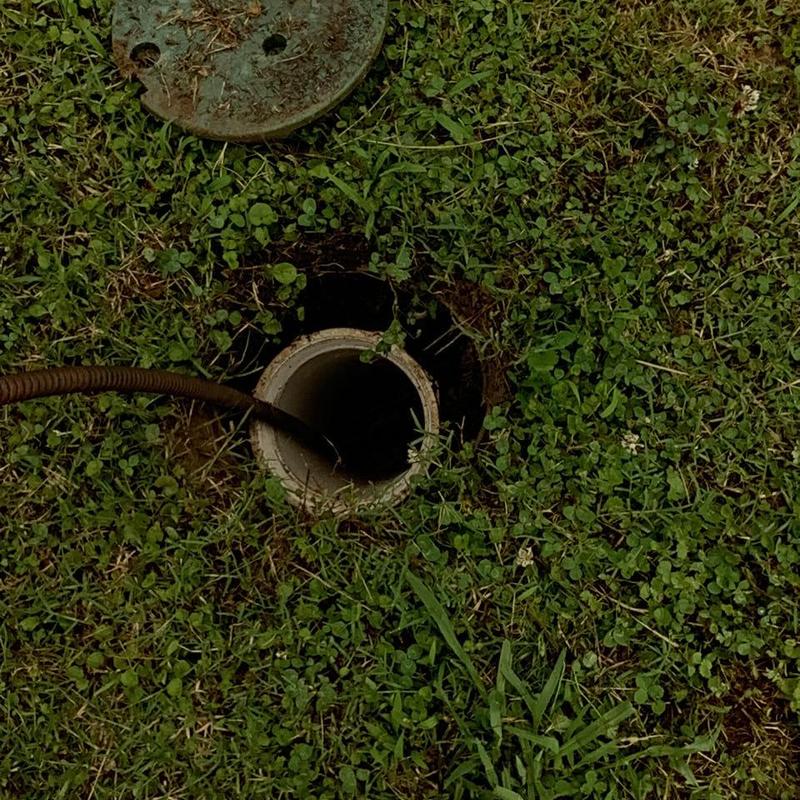 Main sewer line cleanout with cable snake in grass Main sewer line cleanout with cable snake in grass