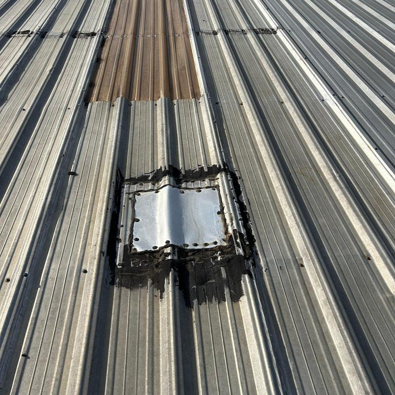 Metal roof panel patch with sealant on industrial roof