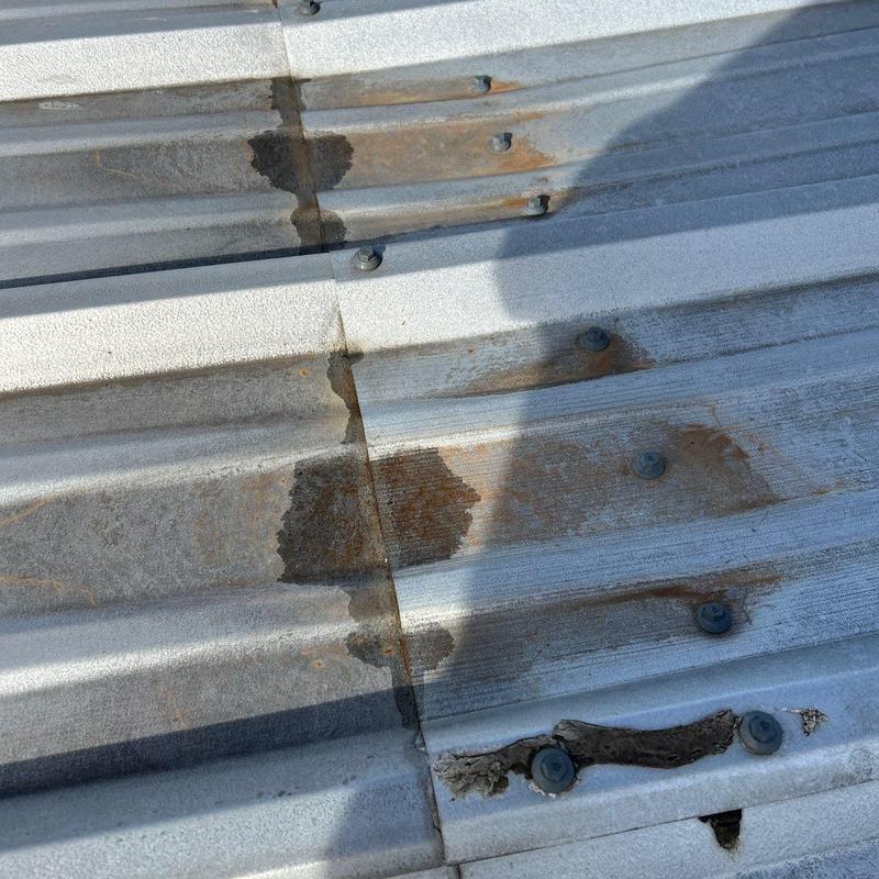 Corrugated metal roof damage with rust and sealant
