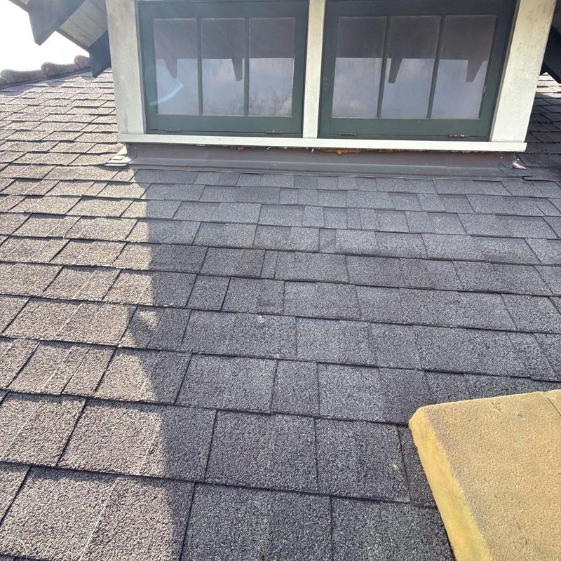 Asphalt roof shingles with hail damage near dormer window