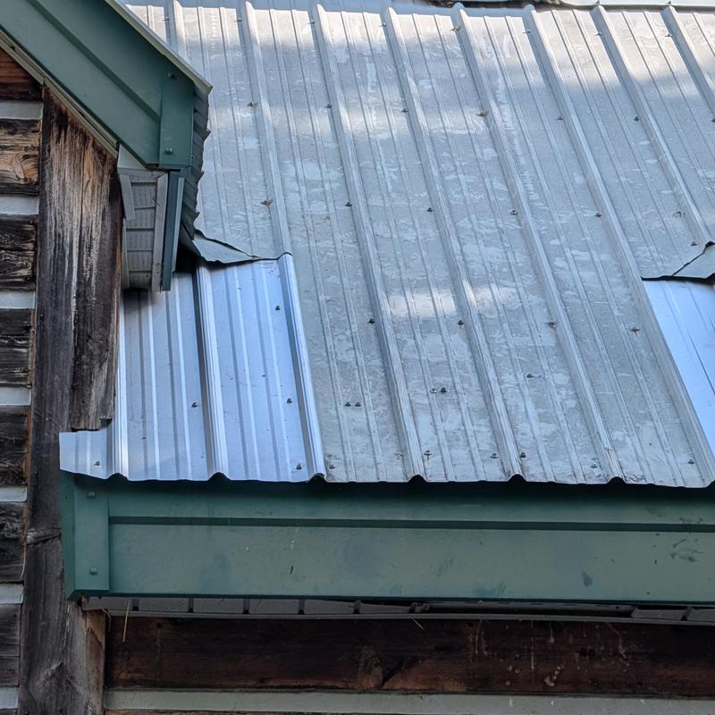 Metal roof panels with improper overlaps on barn roof