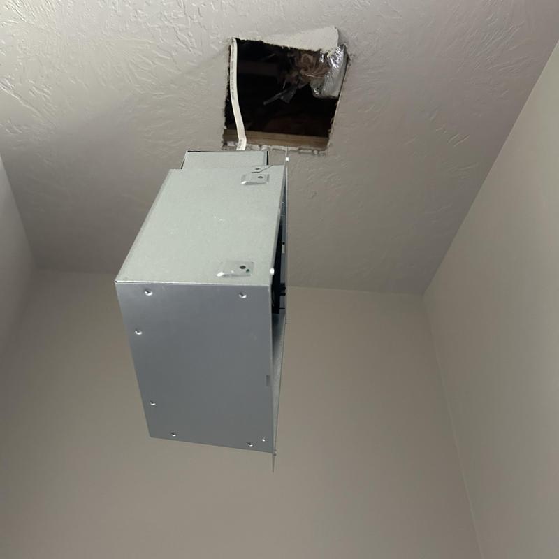 Bathroom exhaust fan housing hanging from ceiling opening