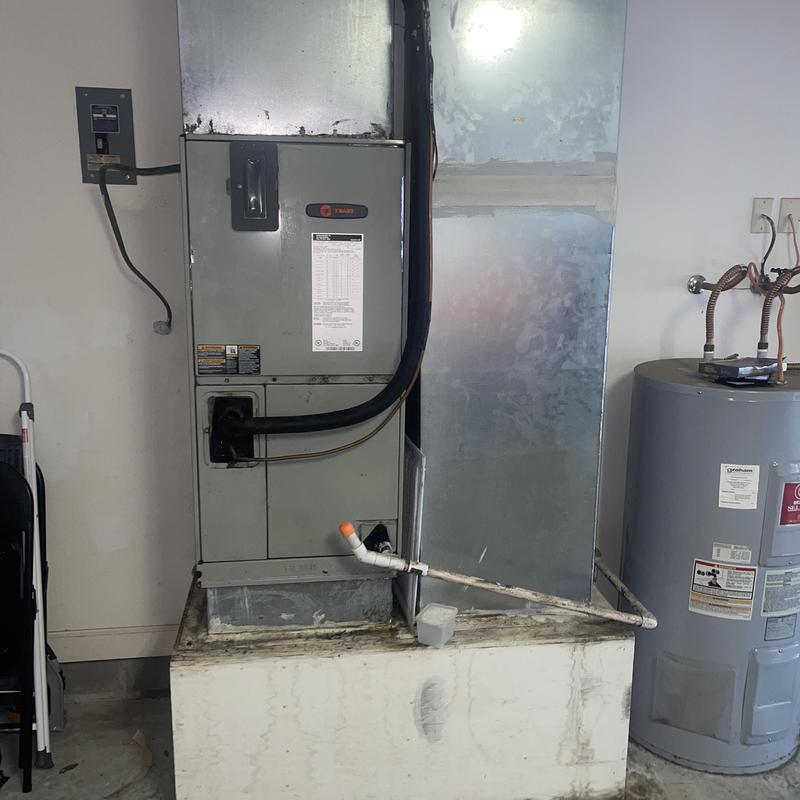 Trane HVAC air handler unit near water heater in garage