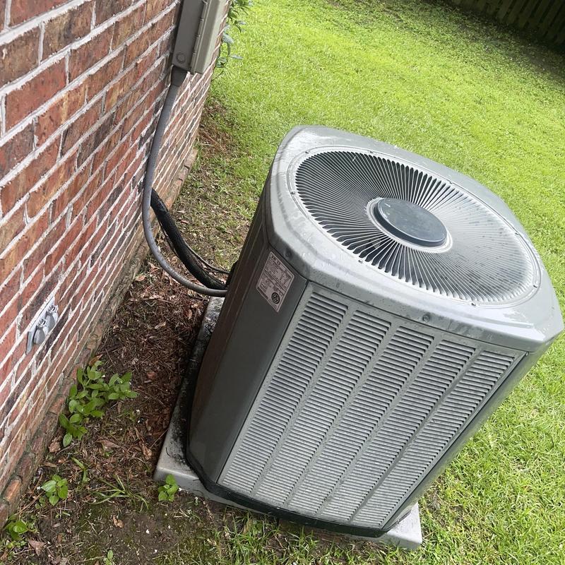 Air conditioner condenser unit outside brick house