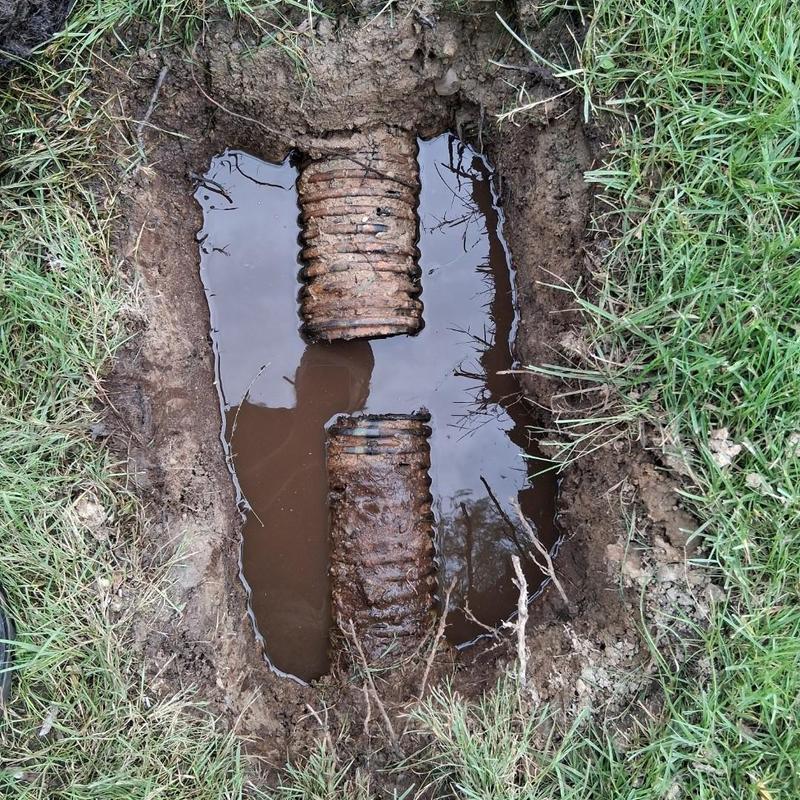 Cable drain tile with water and roots in soil hole Cable drain tile with water and roots in soil hole