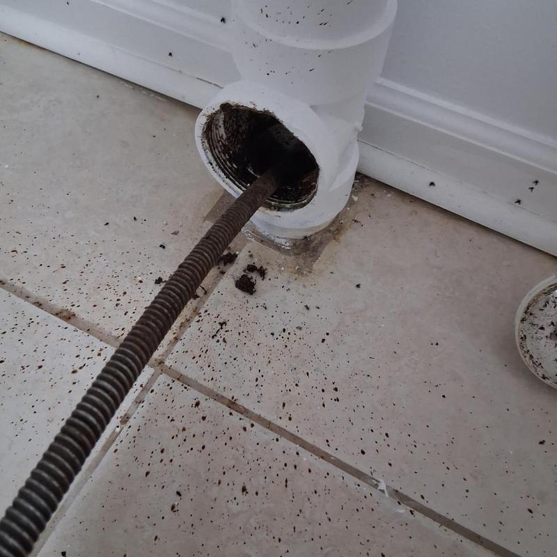 Drain pipe cable snake clearing debris on tiled floor Drain pipe cable snake clearing debris on tiled floor