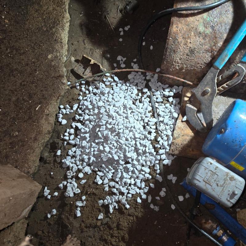 Shallow well head capped with gravel and tools nearby Shallow well head capped with gravel and tools nearby