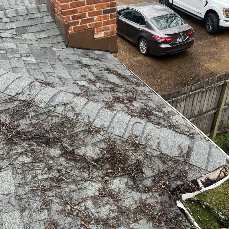 Roof shingles with debris and gutter damage near chimney