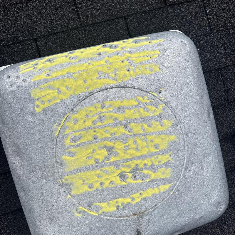 Roof vent cover with hail damage and yellow markings