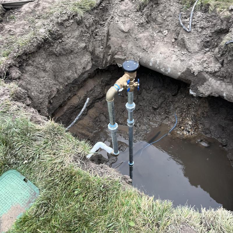 Backflow assembly and water service piping in excavation