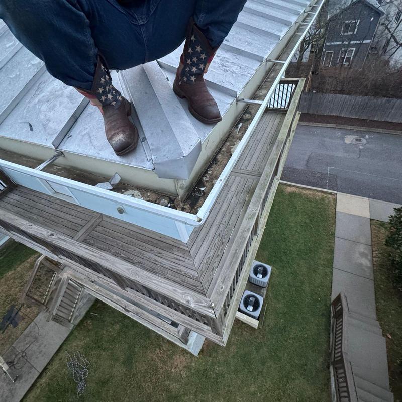 Roof flashing inspection with worker on metal flashing