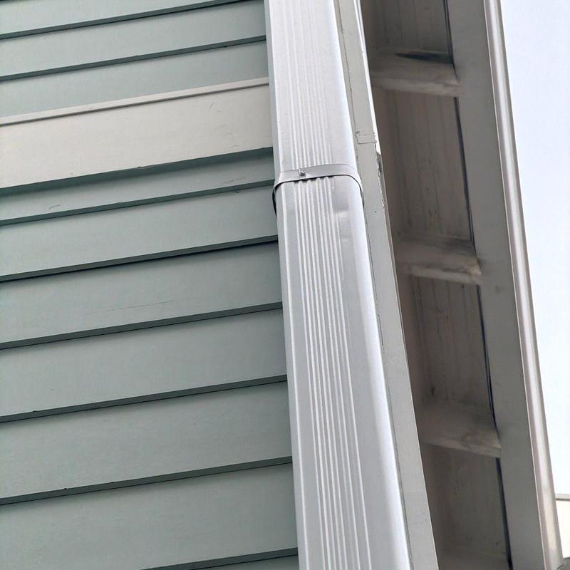 Gutter downspout with securing bracket on siding