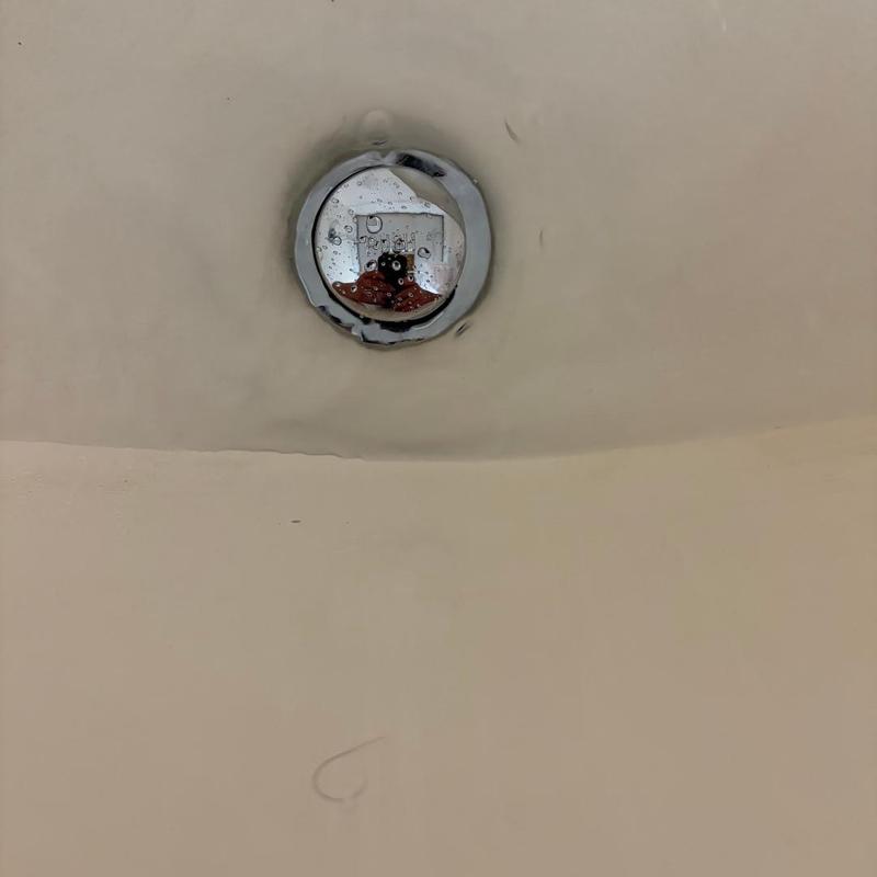 Bathtub stopper with water drops reflecting ceiling light Bathtub stopper with water drops reflecting ceiling light