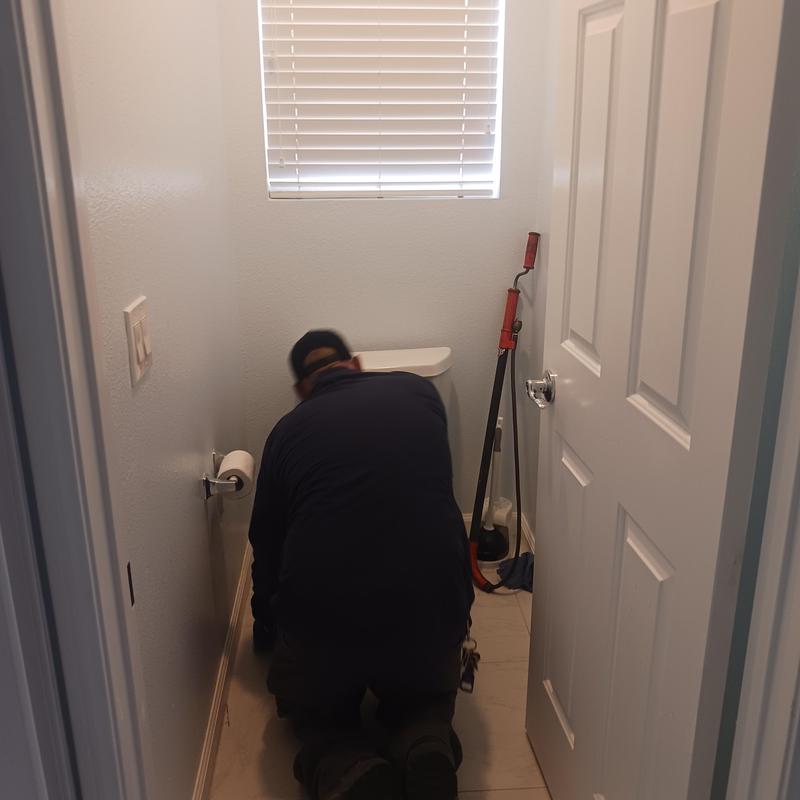 Toilet drain cleaning with plumber kneeling in bathroom Toilet drain cleaning with plumber kneeling in bathroom