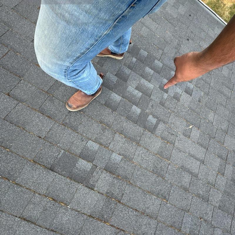Asphalt roof shingles with inspection pointing out issue