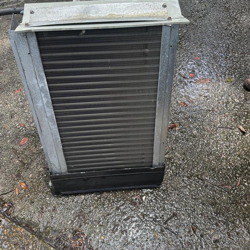 HVAC evaporator coil removed for cleaning on wet ground