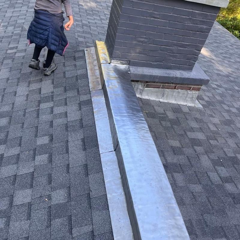 Asphalt shingle roof with metal flashing near chimney Asphalt shingle roof with metal flashing near chimney