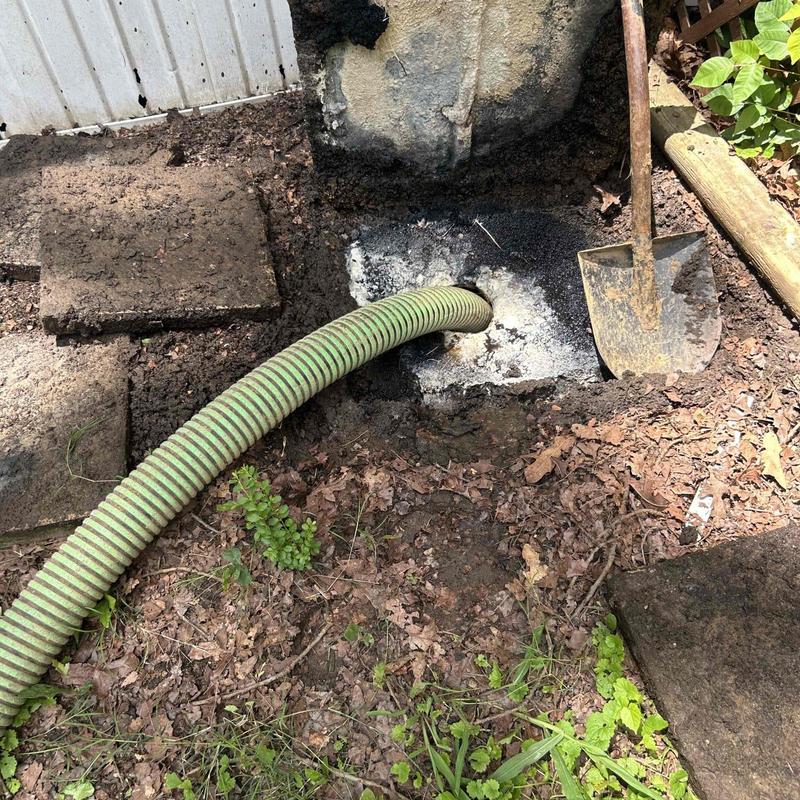 Septic tank pumping with hose and shovel nearby