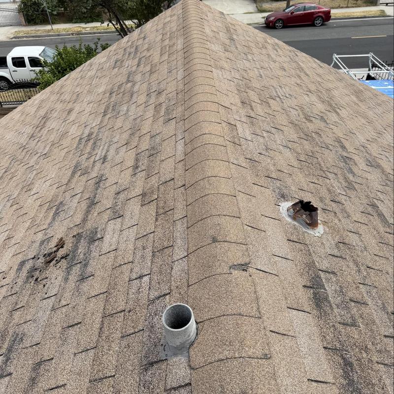 Asphalt shingle roof with vent pipe and damage marks Asphalt shingle roof with vent pipe and damage marks