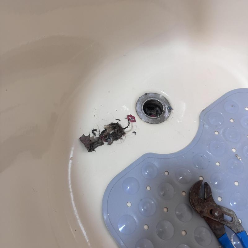Bathtub drain with debris and wrench in tub Bathtub drain with debris and wrench in tub