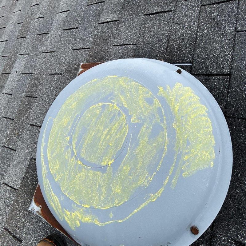 Roof vent cover with hail damage markings on shingles