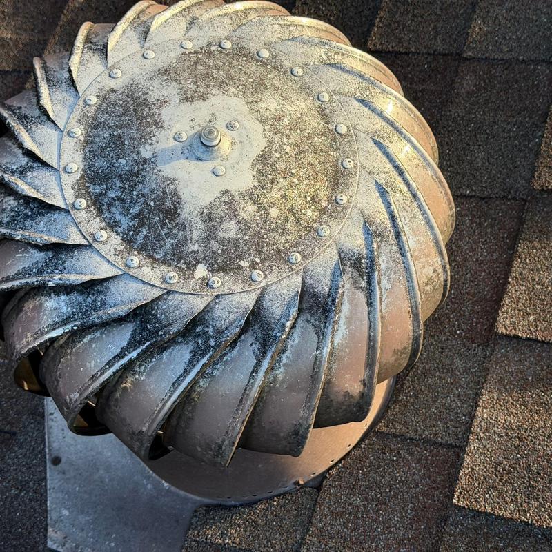 Roof turbine vent with weathered metal blades on shingles