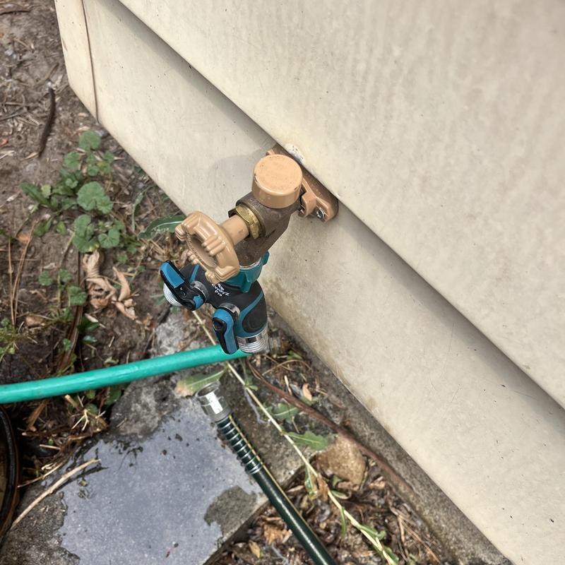 Hose bib with attached garden hose outside home wall Hose bib with attached garden hose outside home wall
