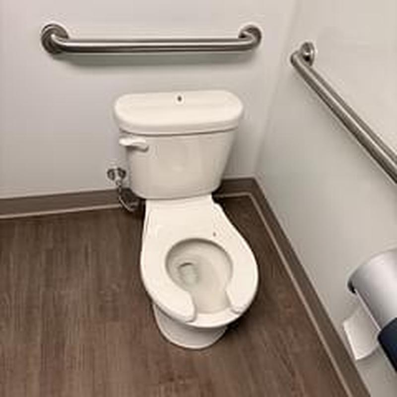 Toilet bowl with safety rails in restroom corner Toilet bowl with safety rails in restroom corner