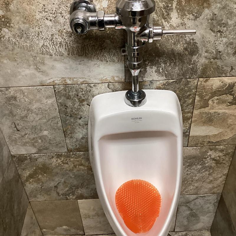 Zurn flush valve on commercial men's urinal