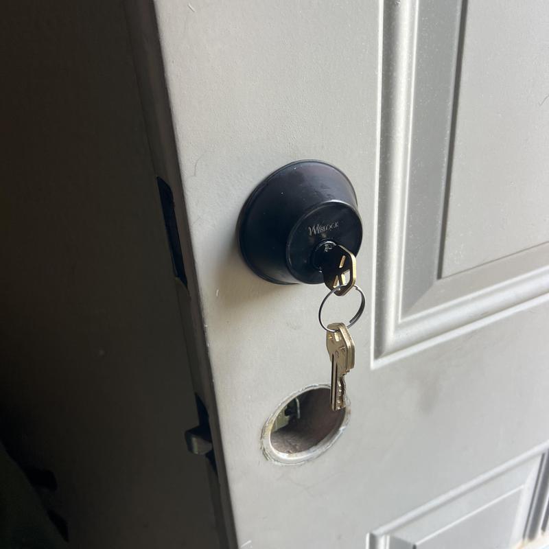 Deadbolt lock with key in white door during rekeying