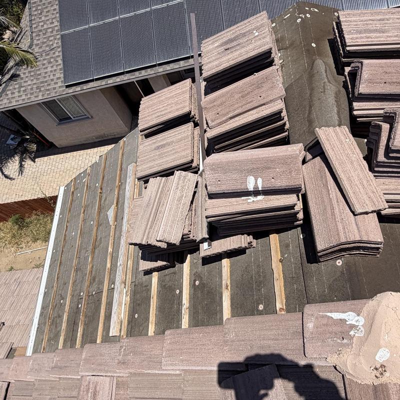Flat roofing tiles stacked for installation on wooden roof deck Flat roofing tiles stacked for installation on wooden roof deck