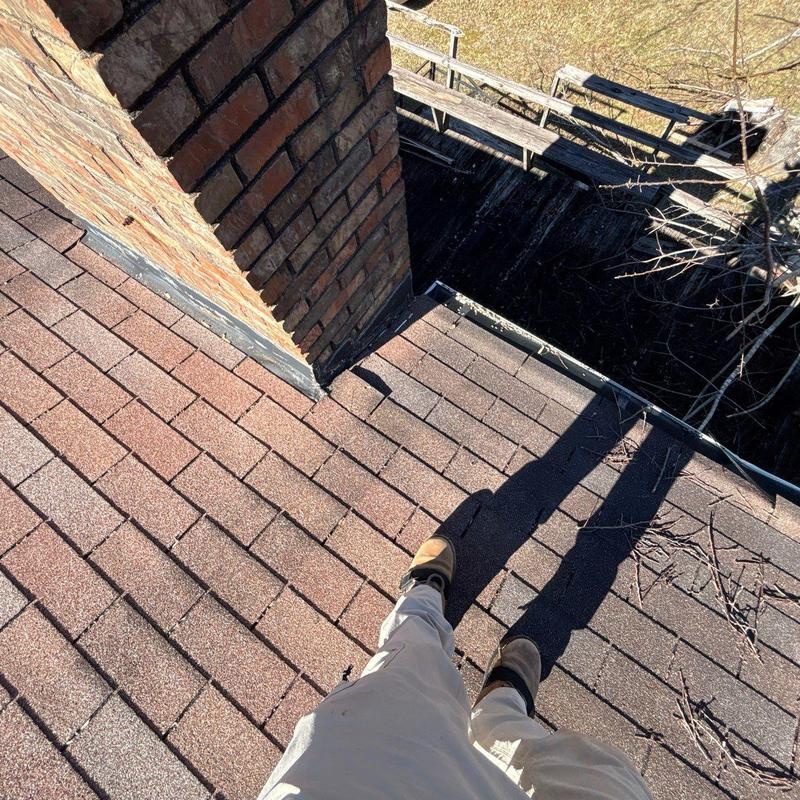 Roof shingles and flashing near brick chimney inspection