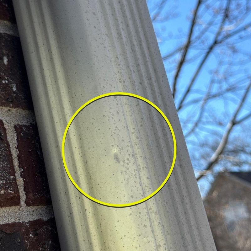Vinyl siding hail damage with impact mark highlighted