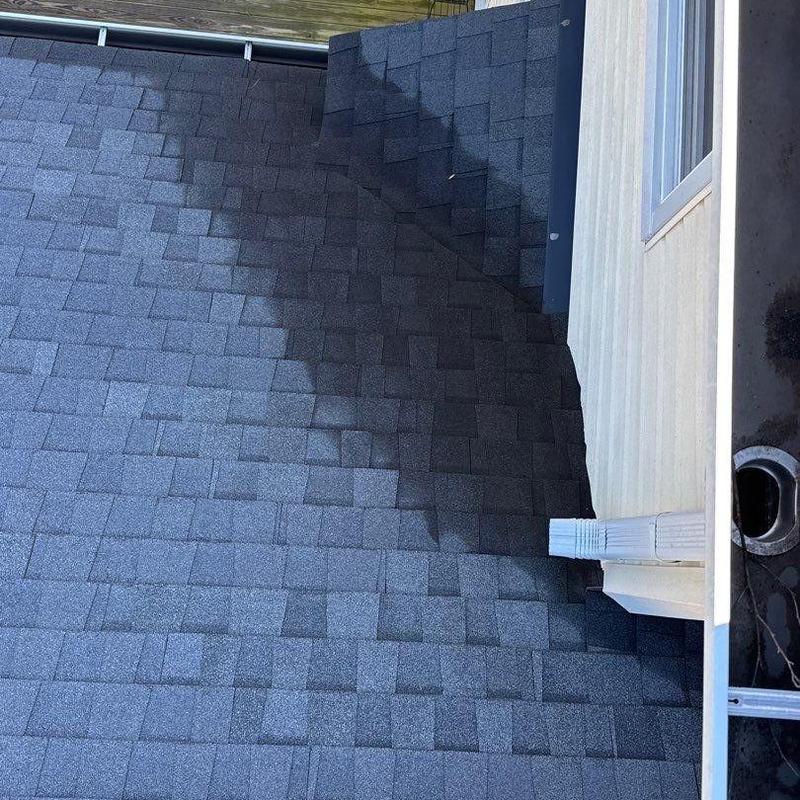 Asphalt shingle roof with hail damage near downspout