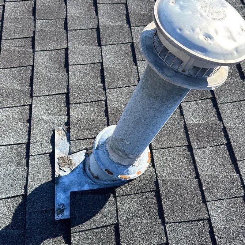 Metal roof vent pipe with hail-damaged shingles and flashing