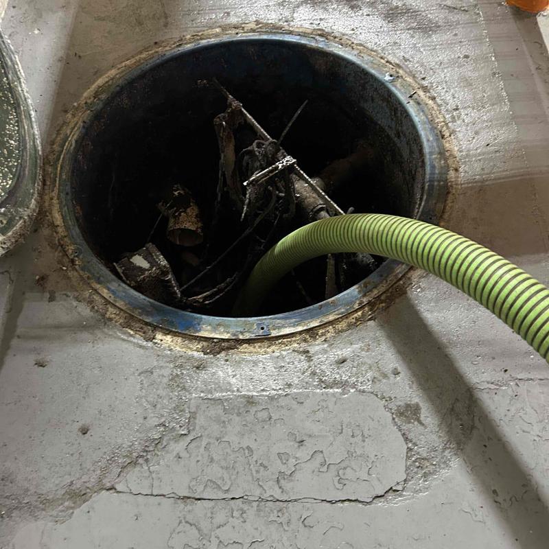 Grinder pump pit with green discharge hose installation