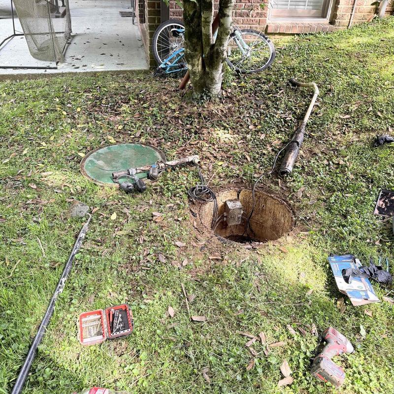 Sump pump system with tools and open pit in yard