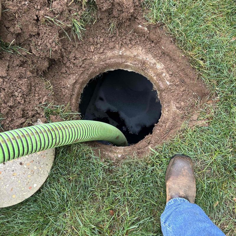 Septic tank opening with green pumping hose and boot