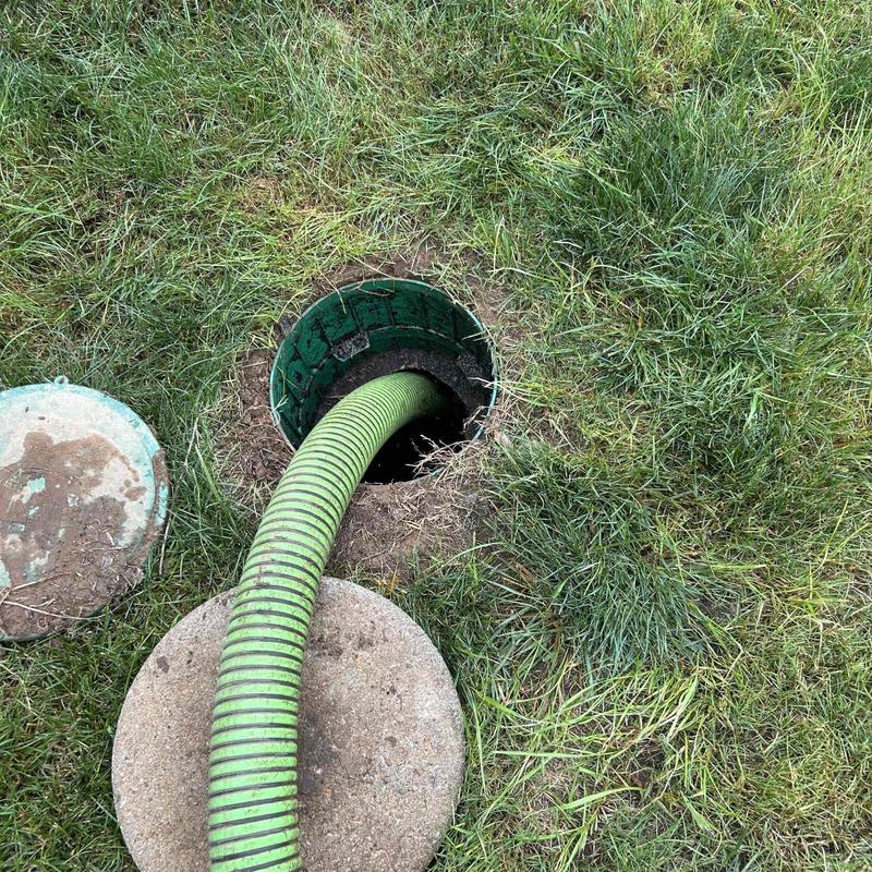 Septic tank pumping hose inserted in ground opening