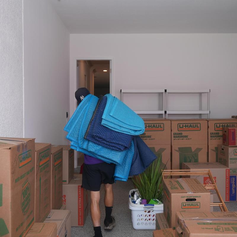 Moving blankets carried by mover among packed boxes Moving blankets carried by mover among packed boxes