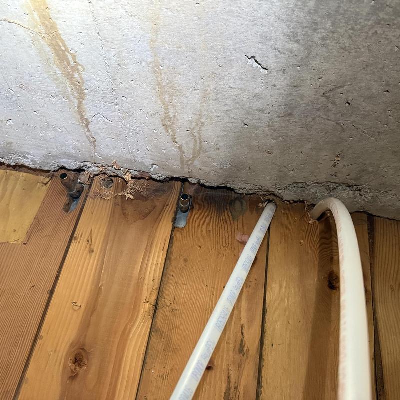 PEX water supply lines near concrete wall and wooden floor
