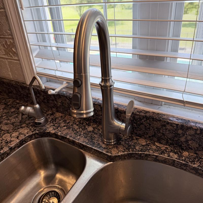 Kitchen faucet installed next to soap dispenser on granite sink