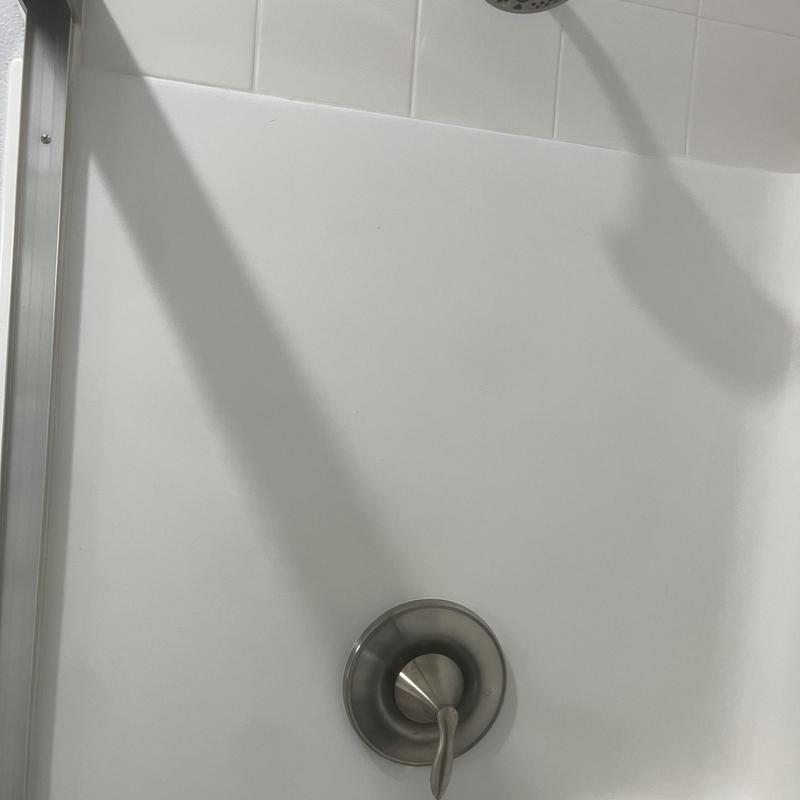 Shower valve and faucet in white tile shower stall